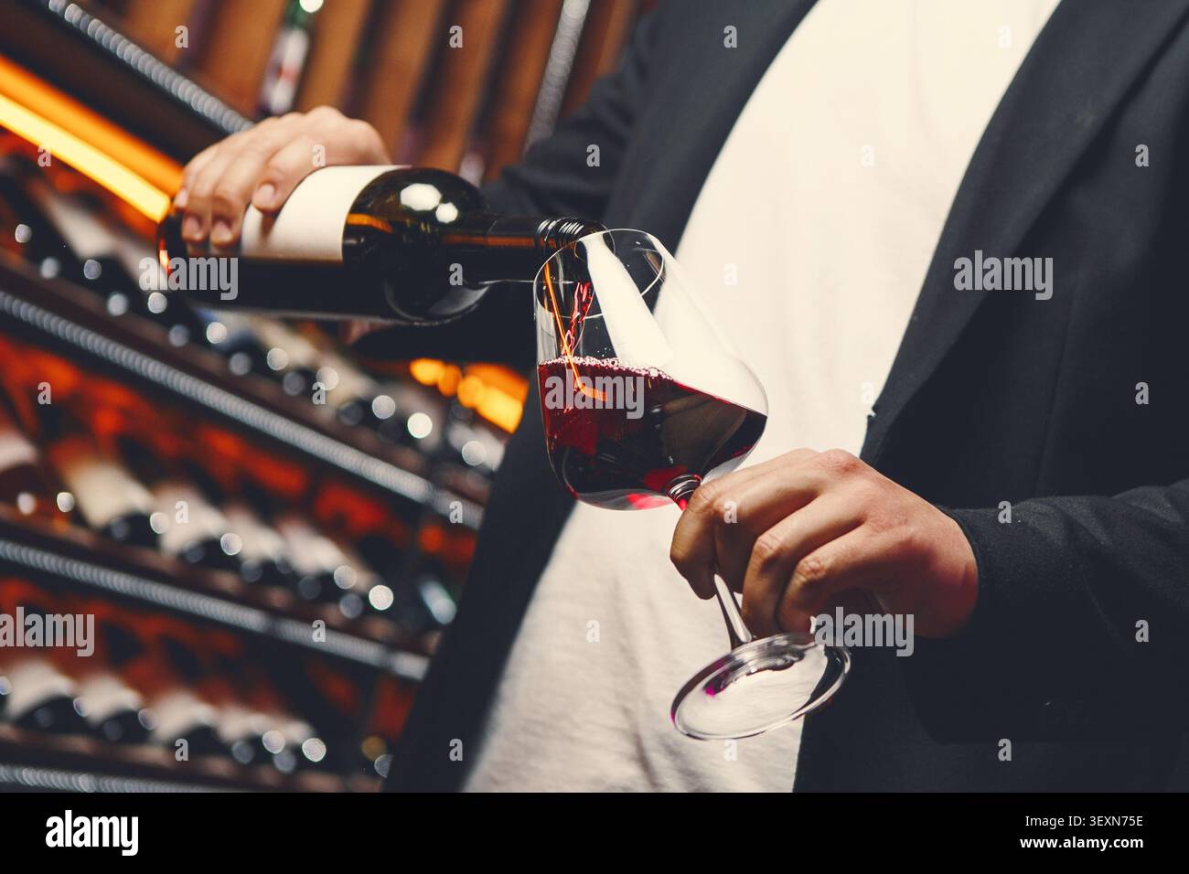 Man in Jacket che versa vino rosso al bar Foto Stock