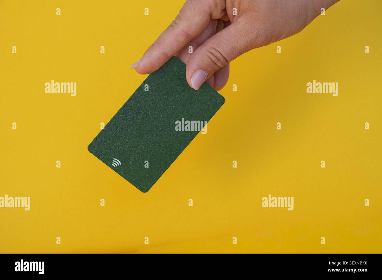 Carta di credito verde in mano su uno sfondo giallo. Spazio per la copia. Foto Stock