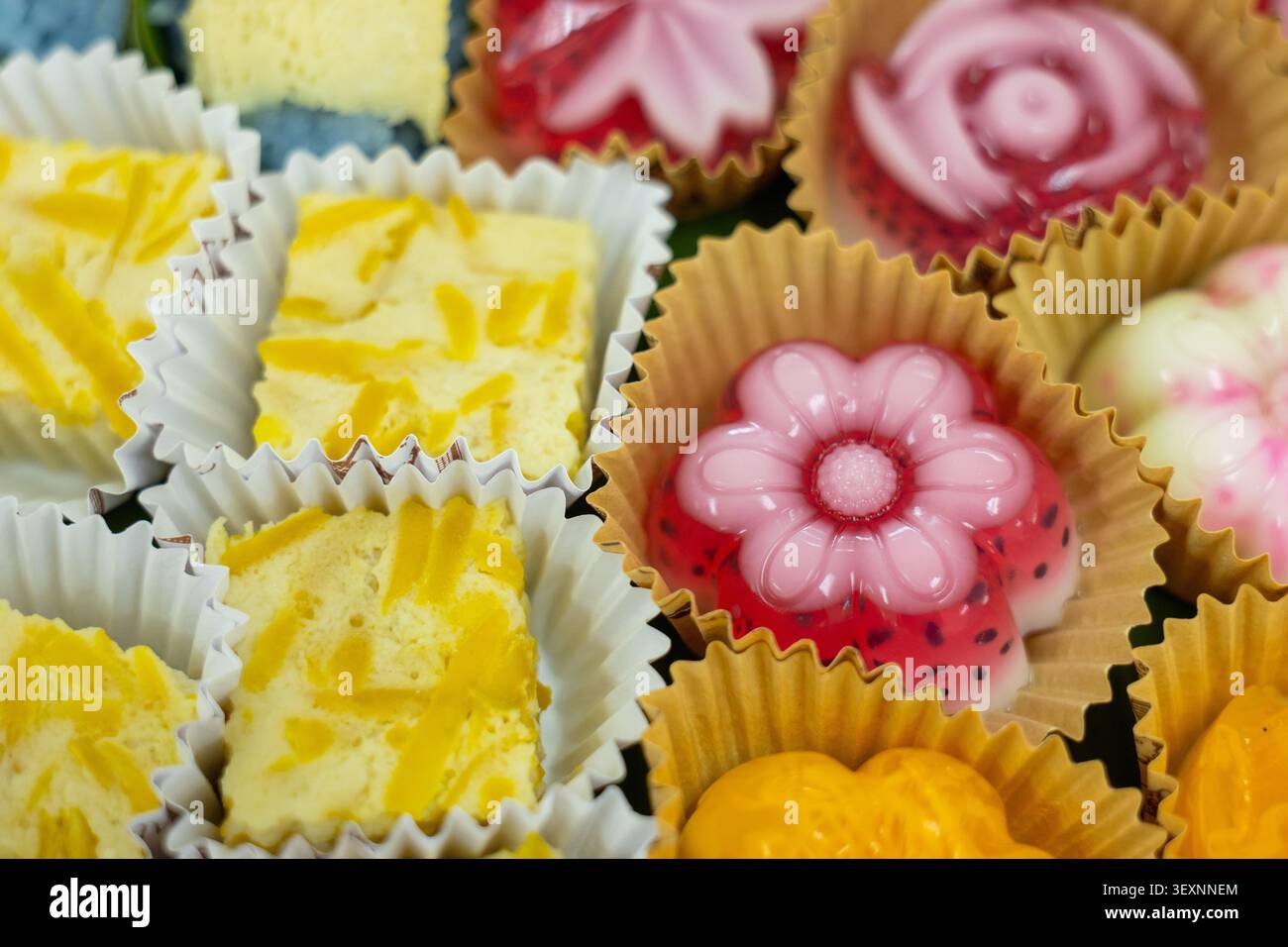 Un colorato dessert thailandese gelatina di fiori di cocco e dolce torta di tuorlo d'uovo in tazza di carta da vicino tradizionale spuntino asiatico festoso delizioso e vibrante che Foto Stock