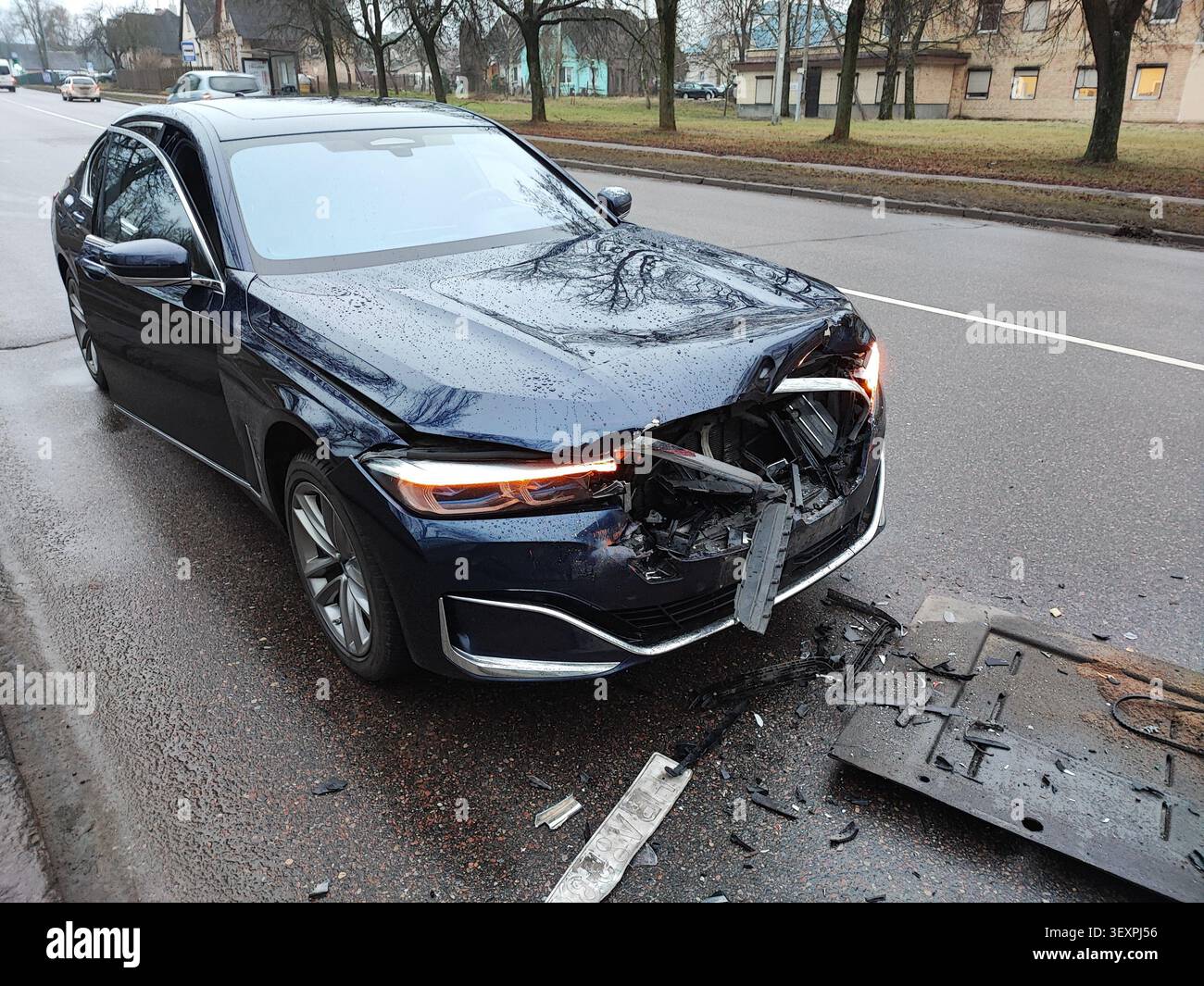 Scena dell'incidente stradale urbano: Vettura di lusso danneggiata dopo una collisione in piedi sulla carreggiata tra detriti Foto Stock