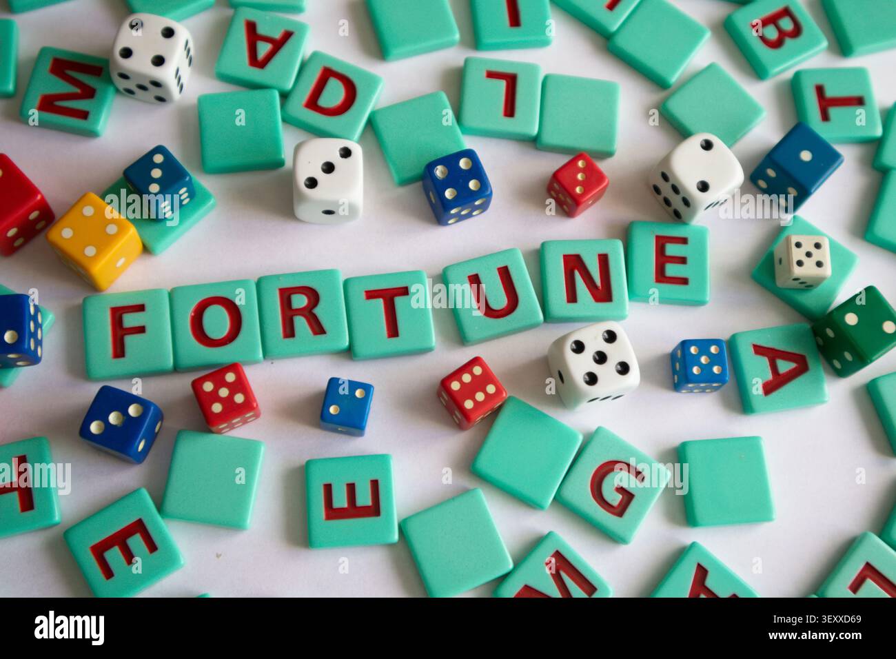 Le tessere delle lettere e i dadi colorati di varie dimensioni sono sparsi su un tavolo. La parola FORTUNA può essere scritta usando alcune tessere. Immagine concettuale Foto Stock