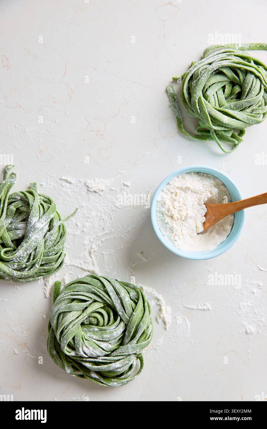 Nidi di pasta fresca fatta in casa con spinaci spolverati di farina su uno sfondo leggero Foto Stock