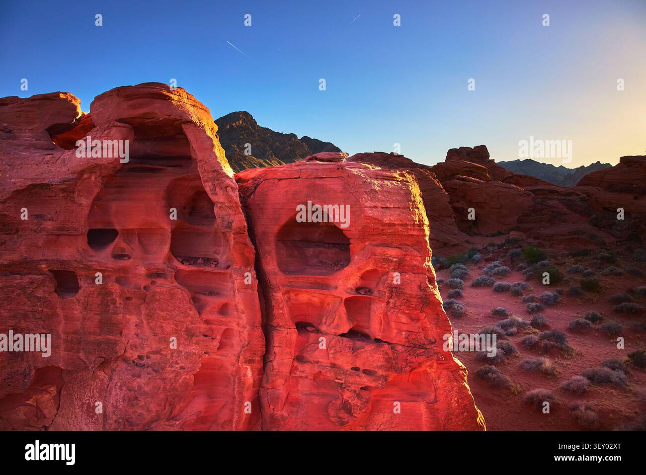 Formazioni di arenaria rossa al tramonto con paesaggio desertico e montagne lontane Foto Stock