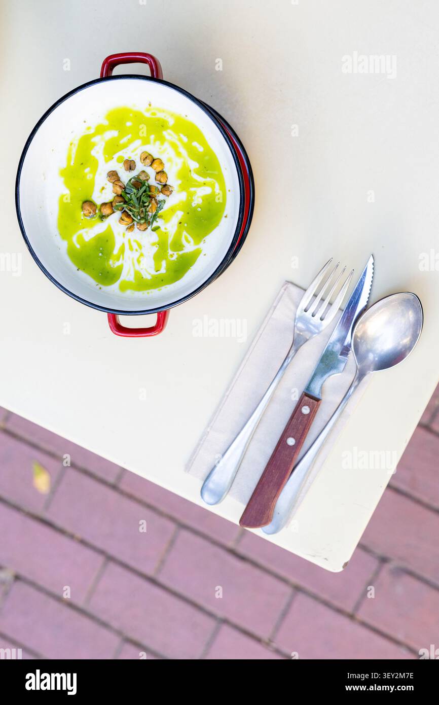 Primo piano di una ciotola calda di cremosa zuppa di broccoli guarnita con panna fresca Foto Stock