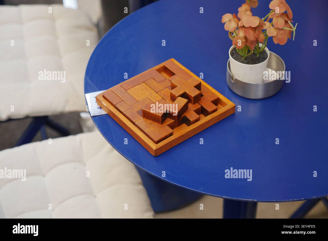 Il puzzle di legno si trova su un tavolo blu accanto a una piccola pianta Foto Stock