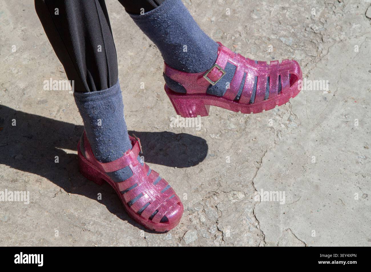 I piedi della donna sono in scarpe e calzini rosa. Stile rustico. Umorismo. Foto Stock