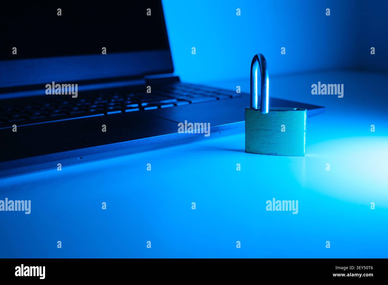 Tastiera per laptop con lucchetto aperto che simboleggia la protezione dei dati online sotto la luce blu Foto Stock