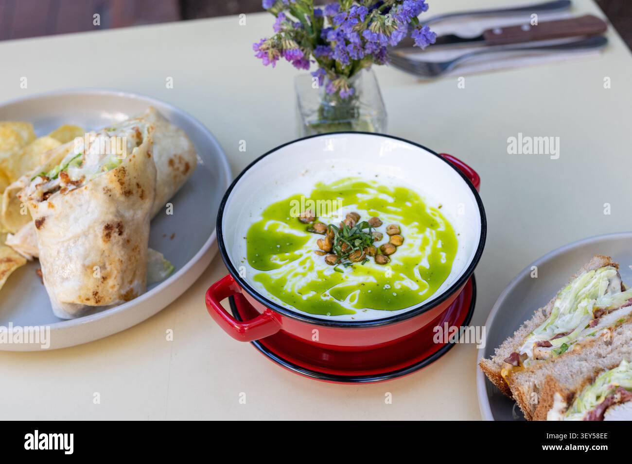 Primo piano di una ciotola calda di cremosa zuppa di broccoli guarnita con panna fresca Foto Stock