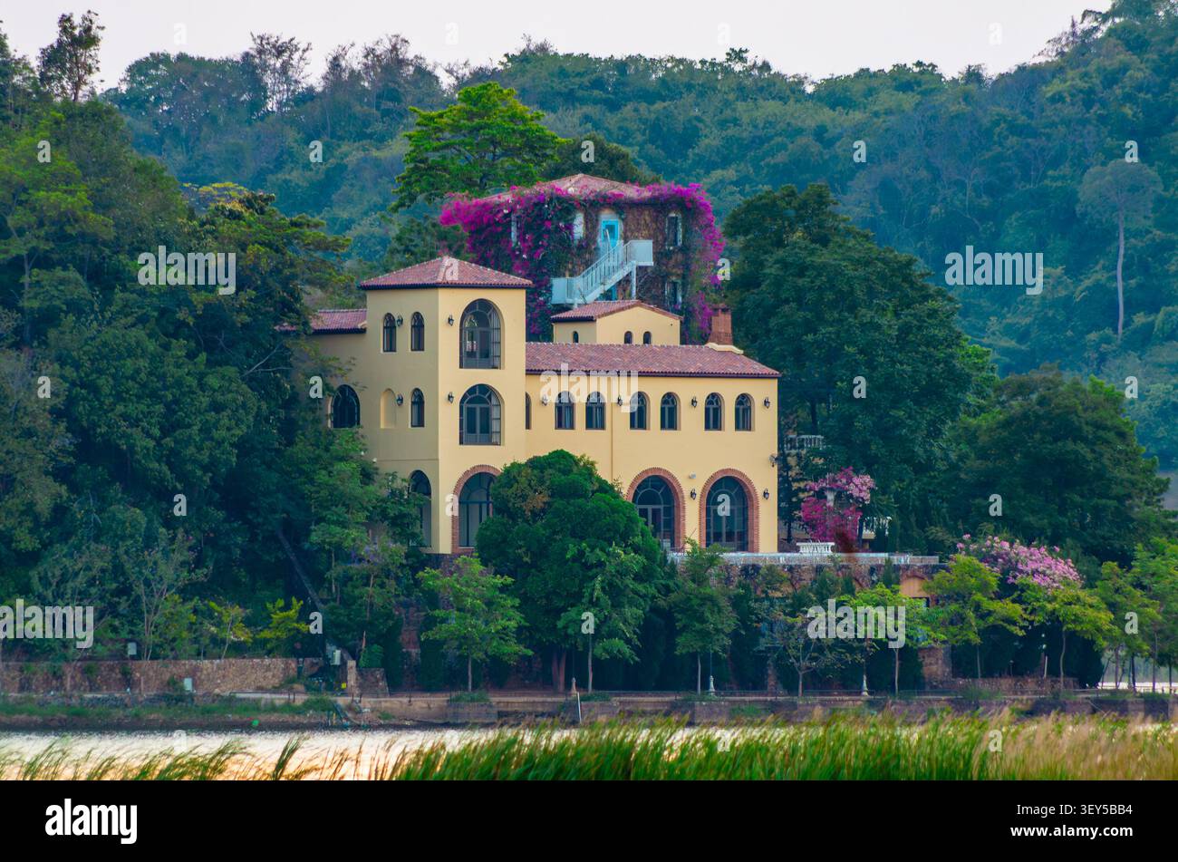 Pattaya, Thailandia - 18 aprile 2026: Una villa Chi Chan con facciata gialla e fiori di bougainvillea visibili dal lungomare, circondata da tropicali Foto Stock
