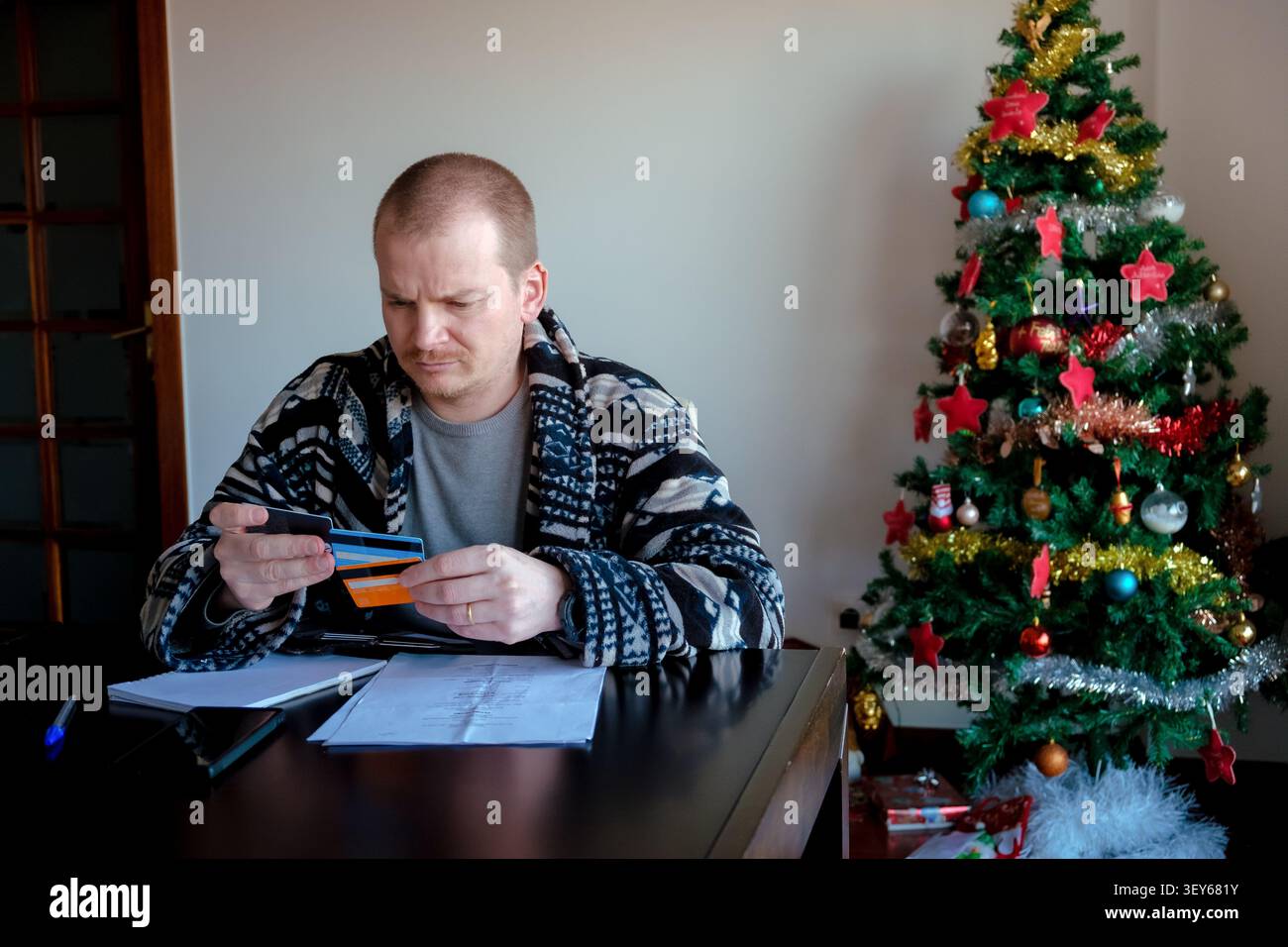 Uomo che ha carte di credito e che calcola le spese, che affronta lo stress finanziario durante il natale Foto Stock