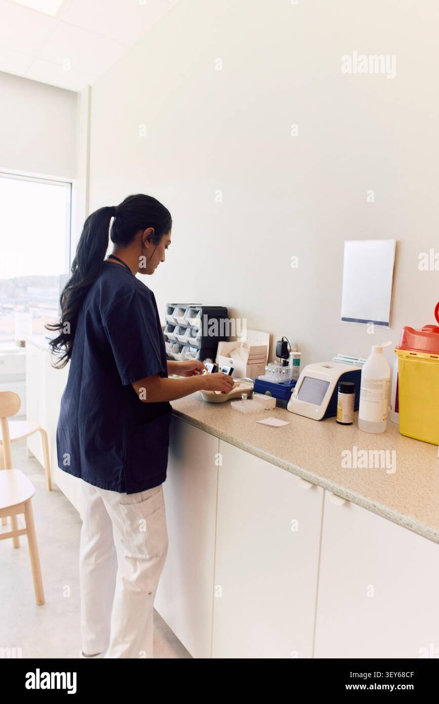 Lavoratore sanitario donna che prepara apparecchiature mediche sul banco di laboratorio Foto Stock
