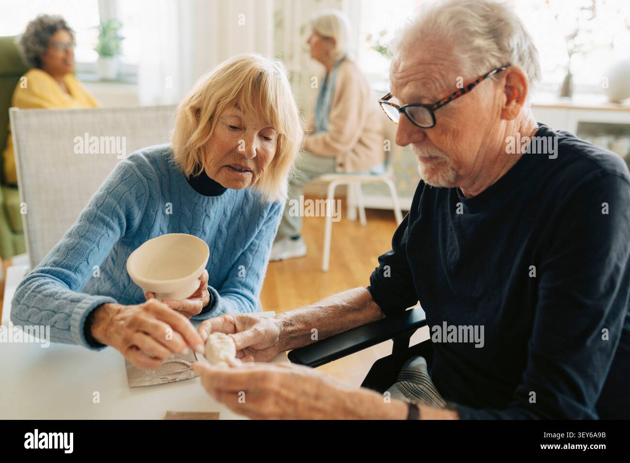 Uomo anziano e donna che lavorano insieme a un progetto di arte della ceramica nella casa di riposo Foto Stock