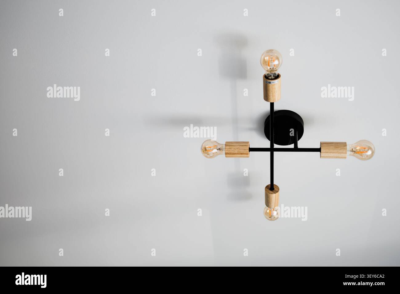 Moderno lampadario nero con accenti in legno sul soffitto bianco Foto Stock