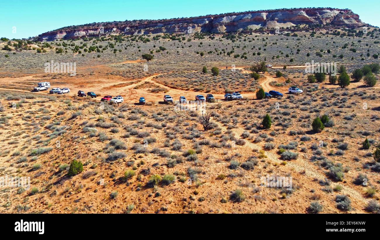 Vista aerea dell'area di parcheggio del deserto e delle scogliere di Mesa. Vista aerea dei veicoli parcheggiati lungo un sentiero polveroso nel deserto con arbusti sparsi e ginepri Foto Stock