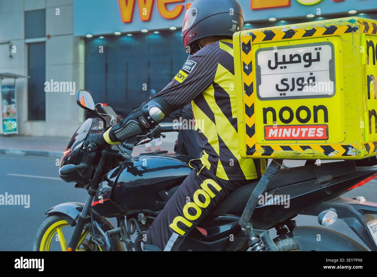Corriere motociclistico a partire da mezzogiorno, servizio di consegna a pochi minuti nel traffico cittadino. Concetto di consegna rapida, logistica dell'ultimo miglio nell'EAS centrale Foto Stock