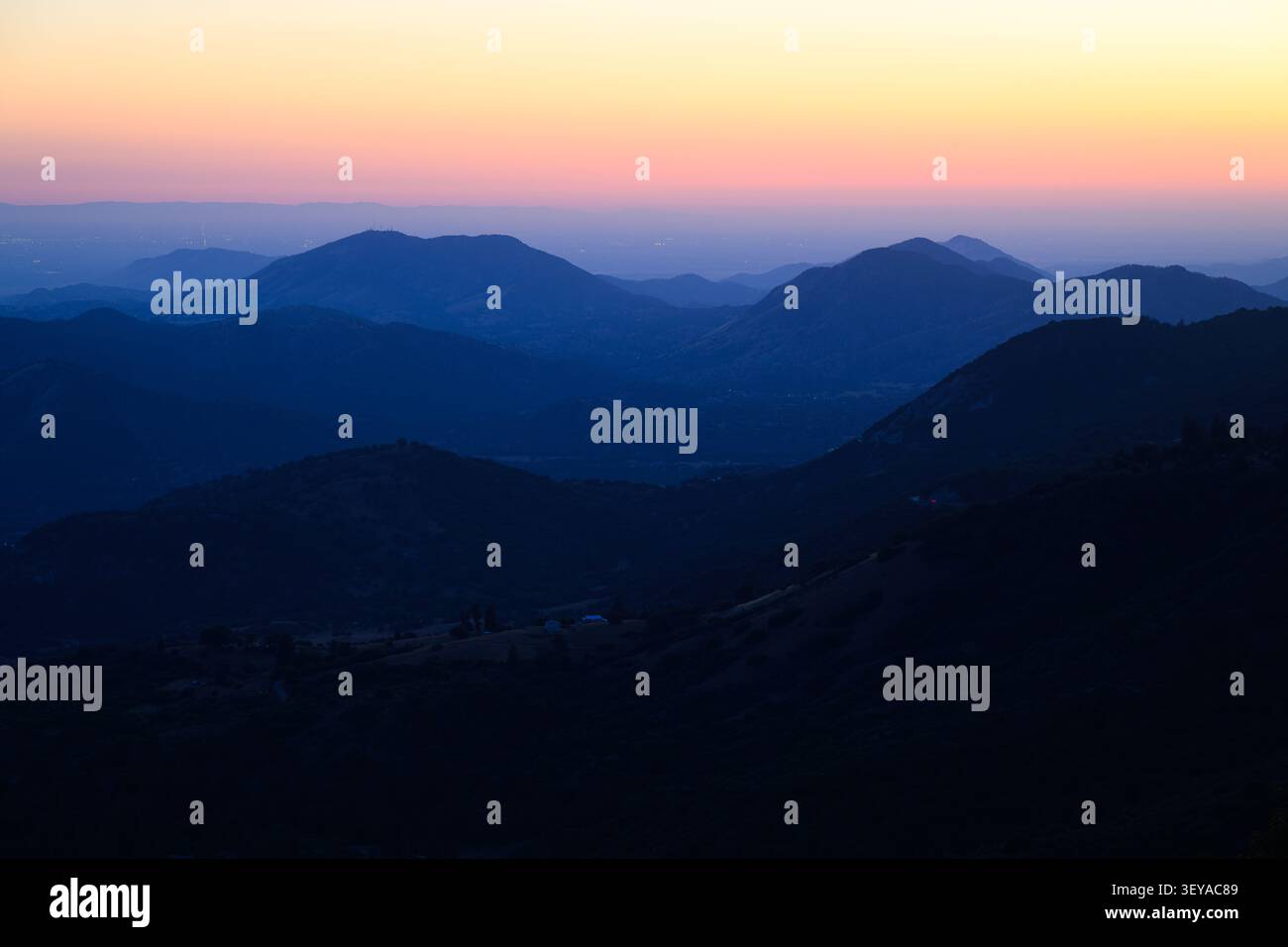 Vista al crepuscolo del caldo bagliore del cielo sopra le colline ai piedi delle montagne della Sierra Nevada nella contea di Fresno, California Foto Stock