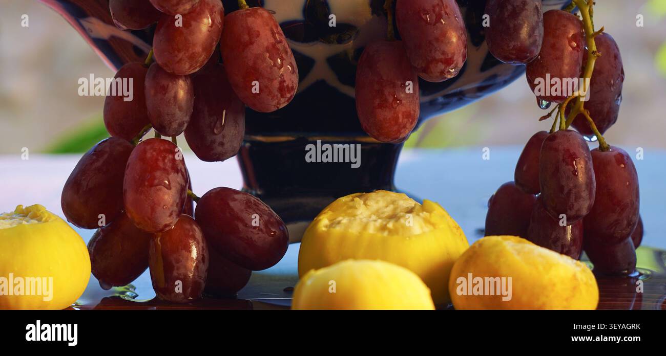 Uva rossa appesa in un vaso, fichi sotto le viti Foto Stock