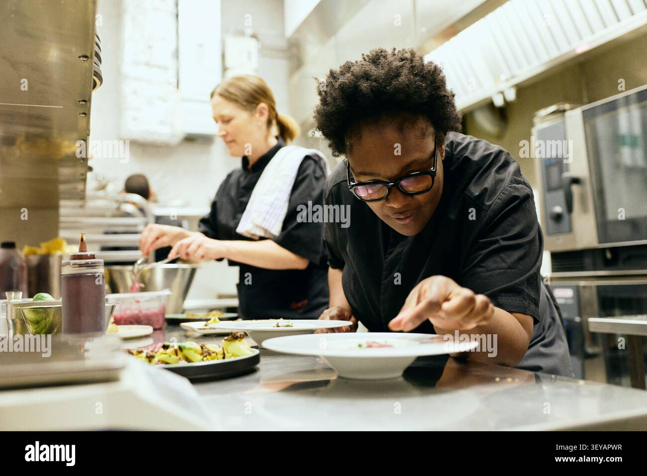 Cibo culinario femminile e professionale mentre lavora all'interno di una cucina commerciale Foto Stock