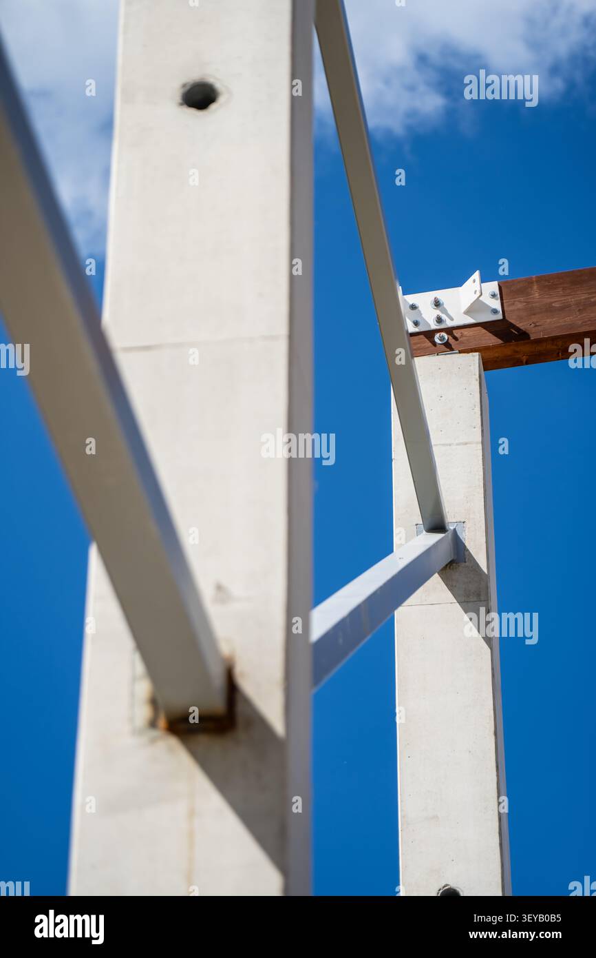 Struttura di costruzione industriale costituita da pali verticali in calcestruzzo e rinforzi metallici collegati a travi in legno per un solido supporto edilizio Foto Stock