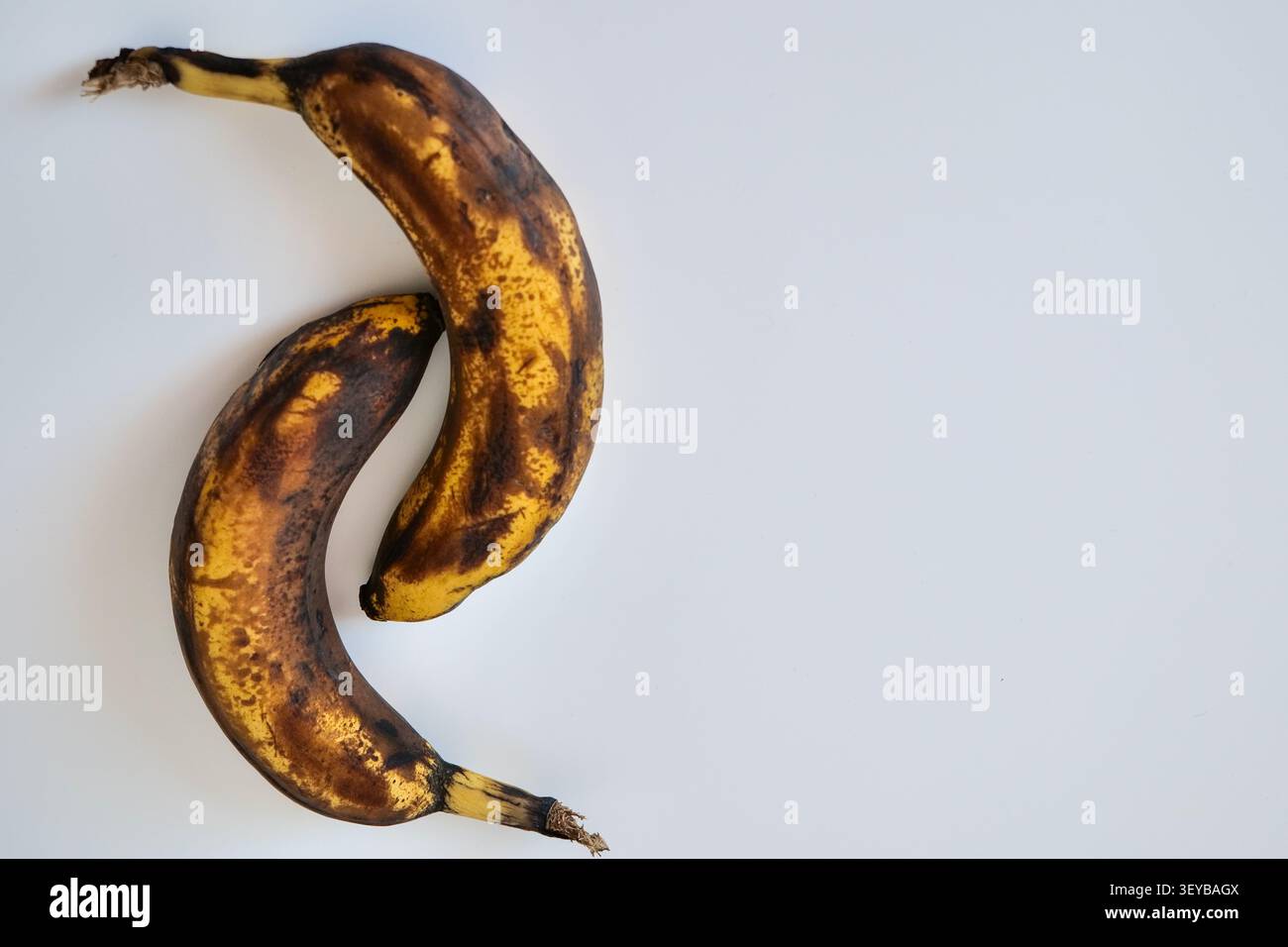 Due banane troppo mature su sfondo bianco Foto Stock