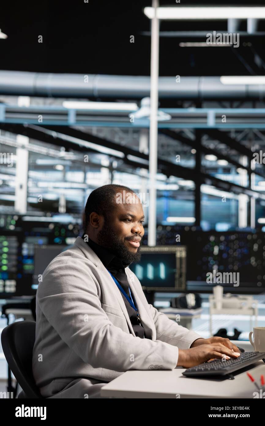 Un esperto IT di strutture server positive lavora con le workstation per aggiornare la tecnologia dei server, configurando le apparecchiature che funzionano con il software. Foto Stock