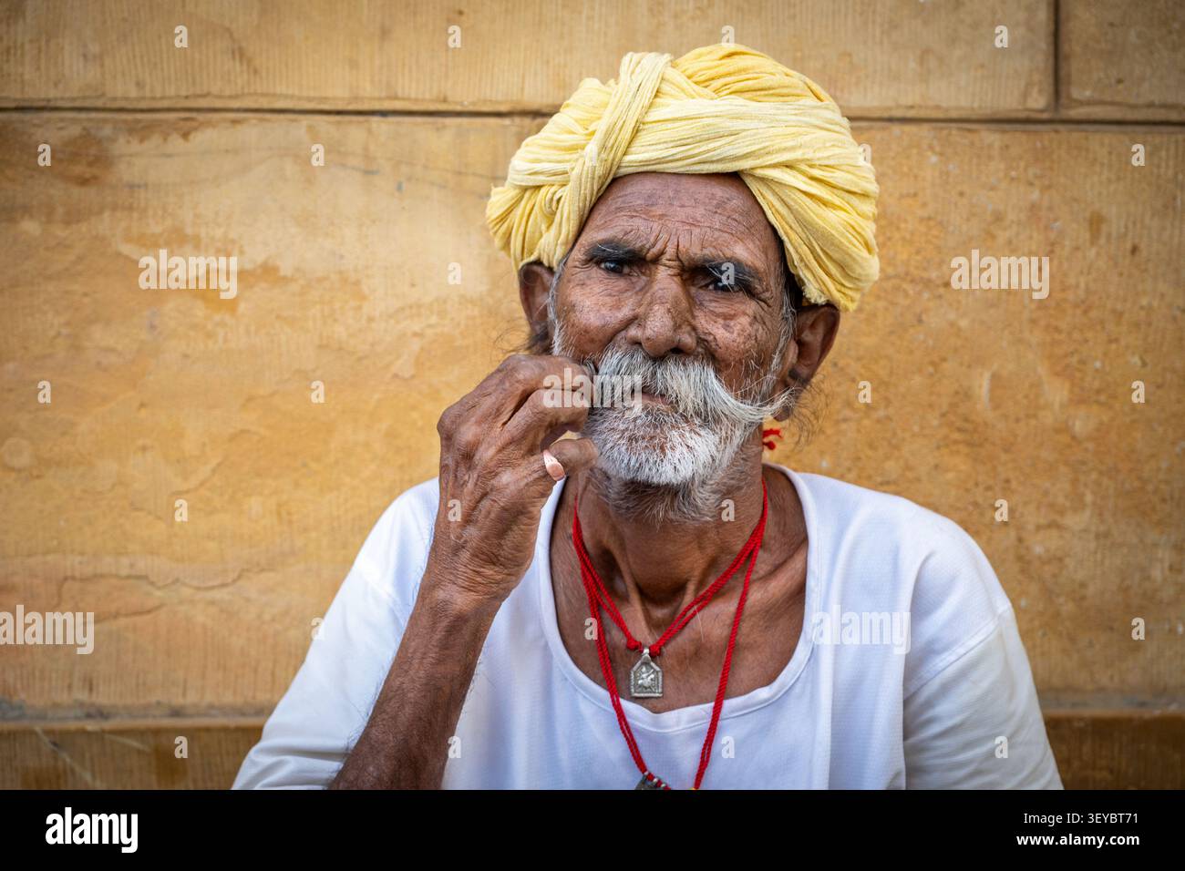 Ritratto di un uomo anziano che si torce i baffi a manubrio e indossa un turbante giallo a Jaisalmer, Rajasthan, India Foto Stock