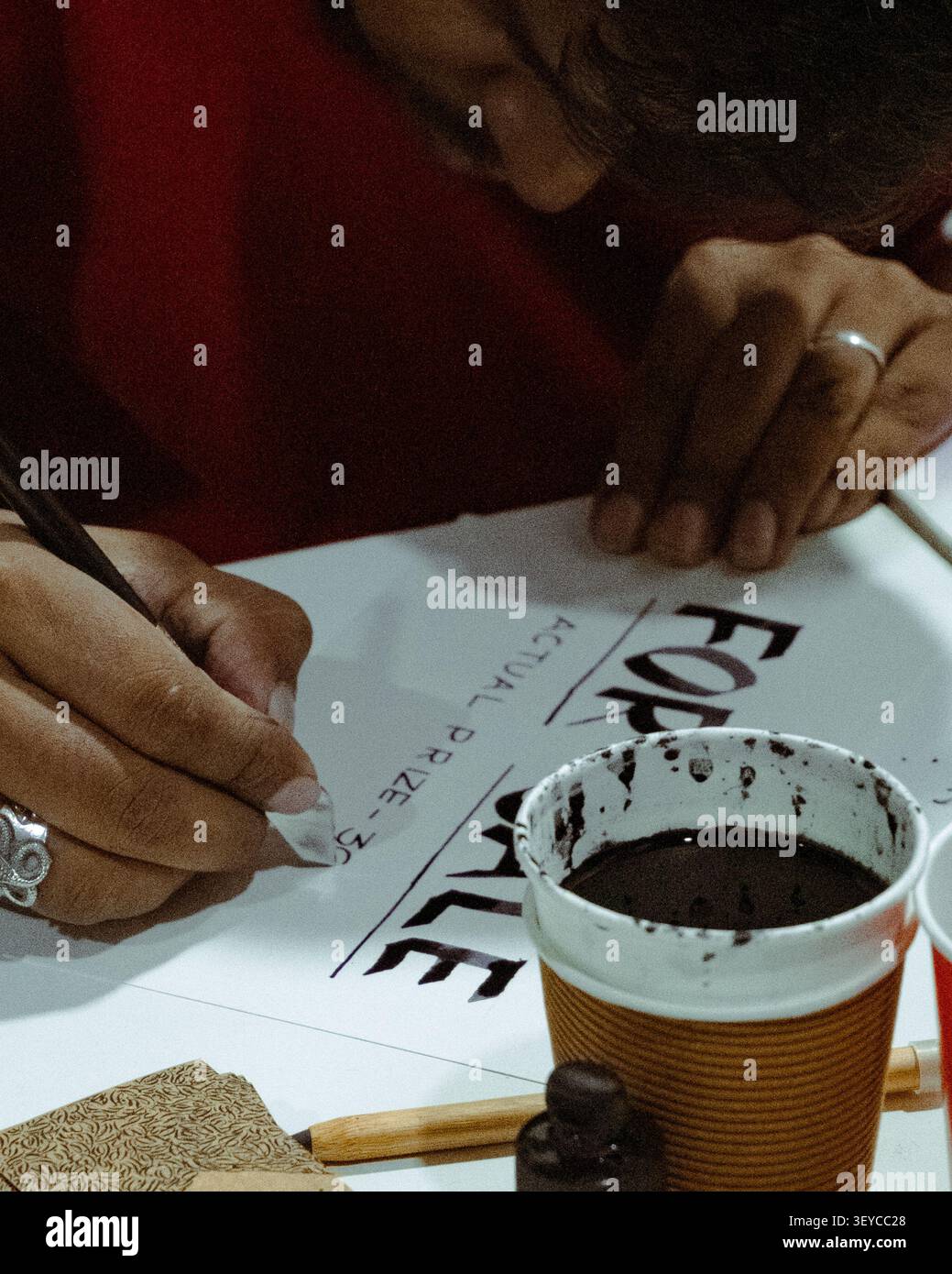 Primo piano di un calligrafo che pratica lettere a mano moderne con una penna a immersione e inchiostro su carta durante un workshop di calligrafia. Foto Stock