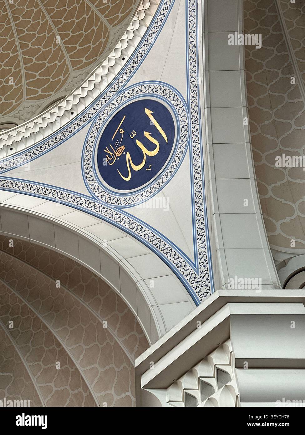 Medaglione di calligrafia araba d'oro su ovale blu scuro, incastonato all'interno di un ornato spandrel ad arco bianco di una moderna moschea. Modelli islamici geometrici, Malesia o. - Immagine stock catturata con smartphone