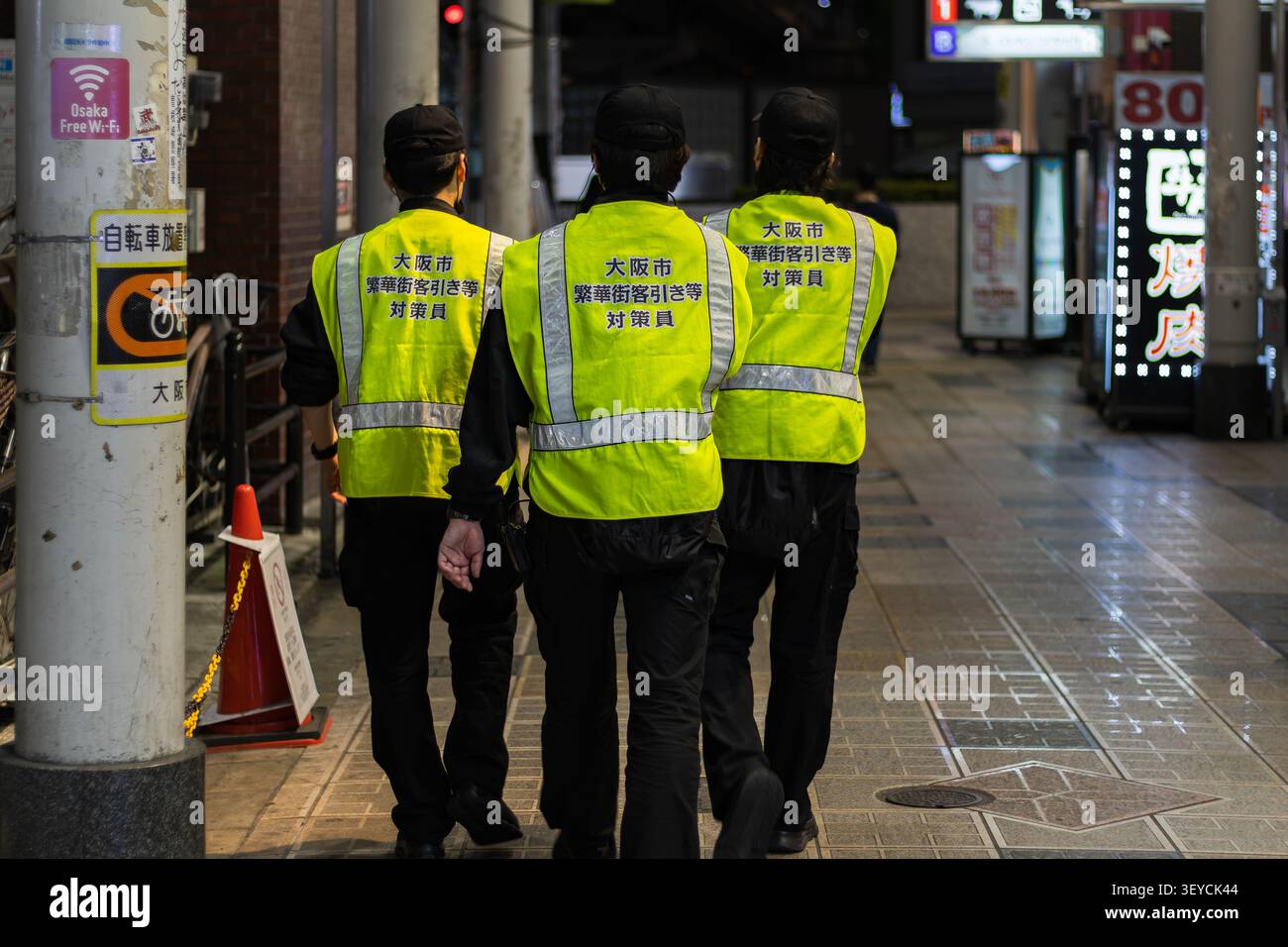 Osaka, Giappone 22 aprile 2026 agenti di pattuglia di pubblica sicurezza che indossano giubbotti riflettenti che camminano attraverso un quartiere di intrattenimento di notte a osaka per urb Foto Stock