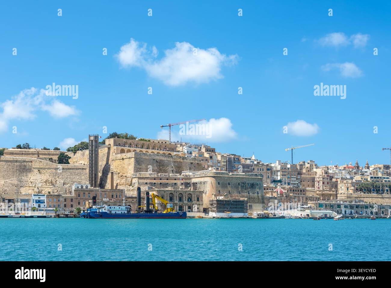 Vista panoramica degli storici bastioni della Valletta e dell'ascensore di Barrakka sopra il Porto grande con fortificazioni in pietra calcarea, lungomare e Mediterr blu Foto Stock