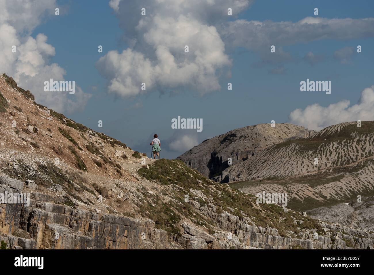 Escursionista solitario in piedi su una cresta montuosa rocciosa contro un cielo nuvoloso drammatico, concetto di avventura selvaggia nelle pittoresche Dolomiti. Foto Stock