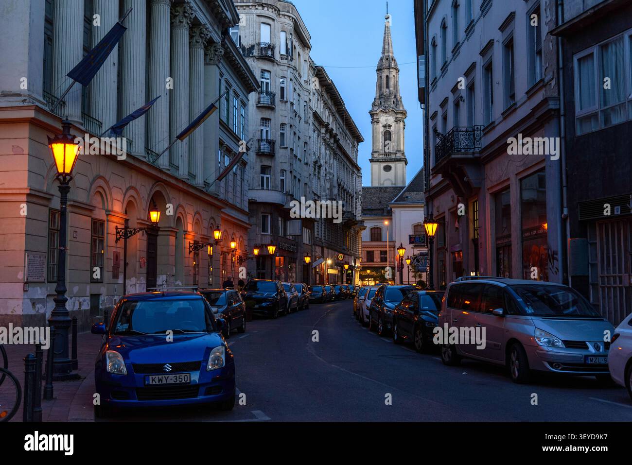 Guardando il campanile della chiesa di Ferenciek tere da una stradina stretta all'ora blu di Budapest Foto Stock