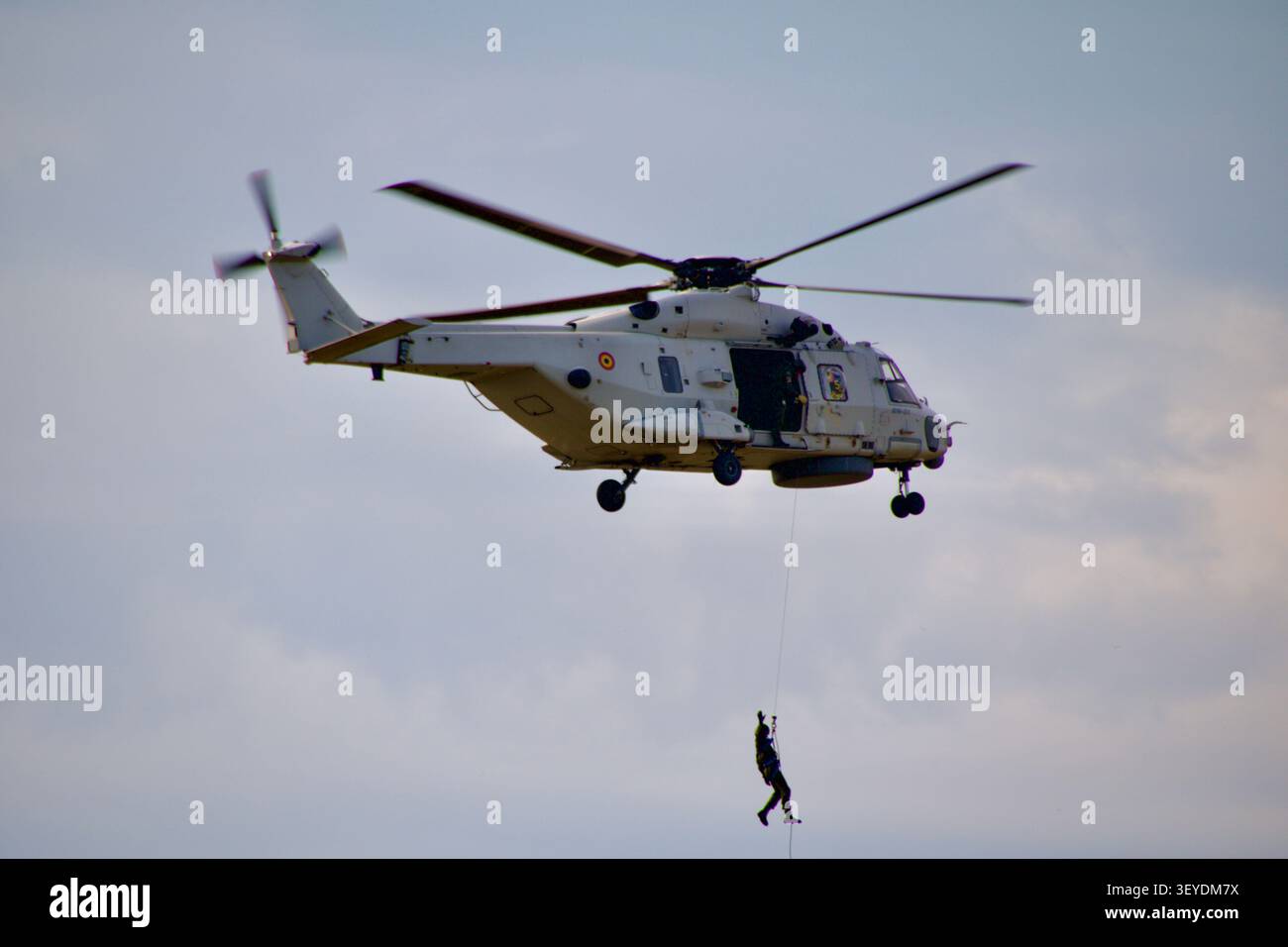 Elicottero NH90 NFH dell'aeronautica belga (registrazione RN-01) che esegue una dimostrazione di sollevamento con verricello di ricerca e soccorso (SAR) contro un cielo nuvoloso. Foto Stock