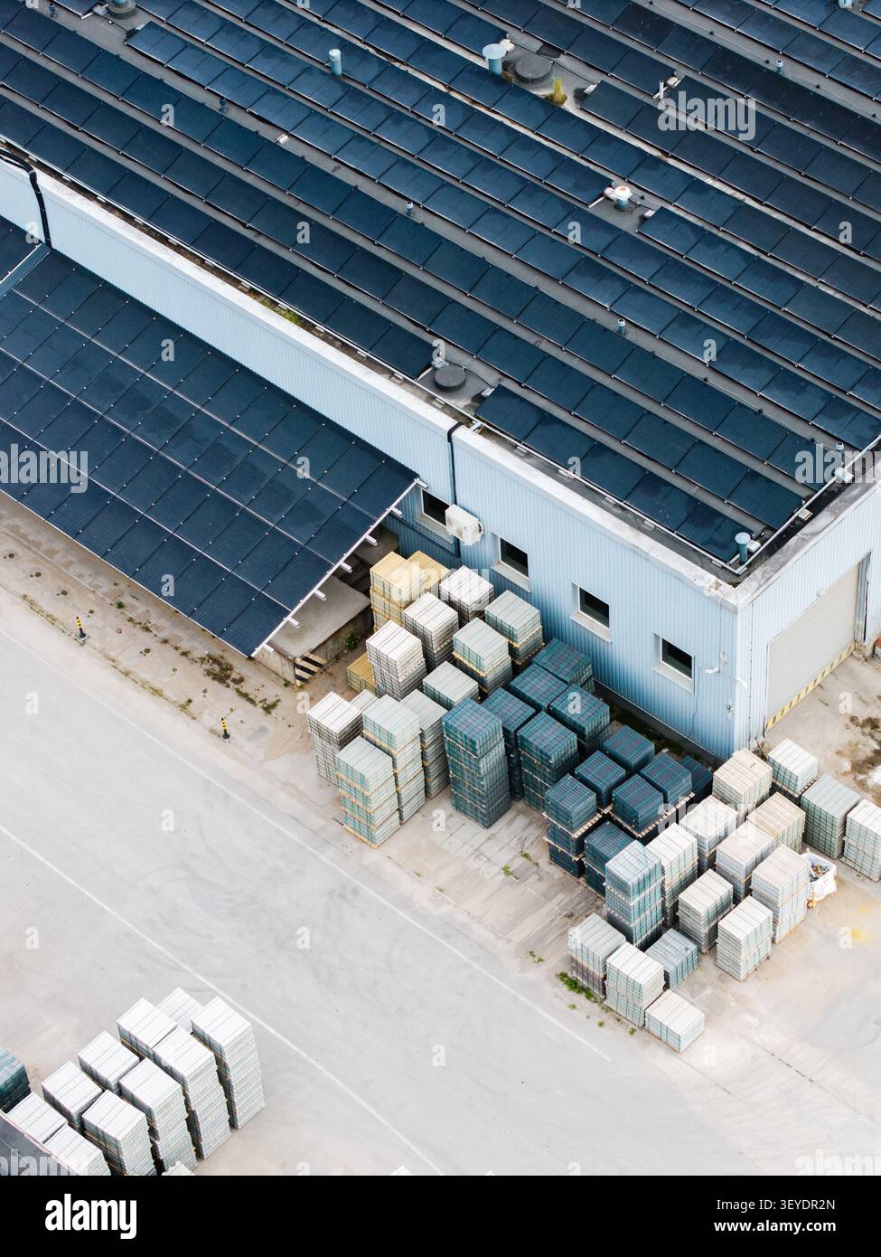 Veduta aerea di una fabbrica di lastre di pavimentazione con pannelli solari sul tetto e pile organizzate di lastricatrici di calcestruzzo nel cantiere industriale di riga, Latvi Foto Stock