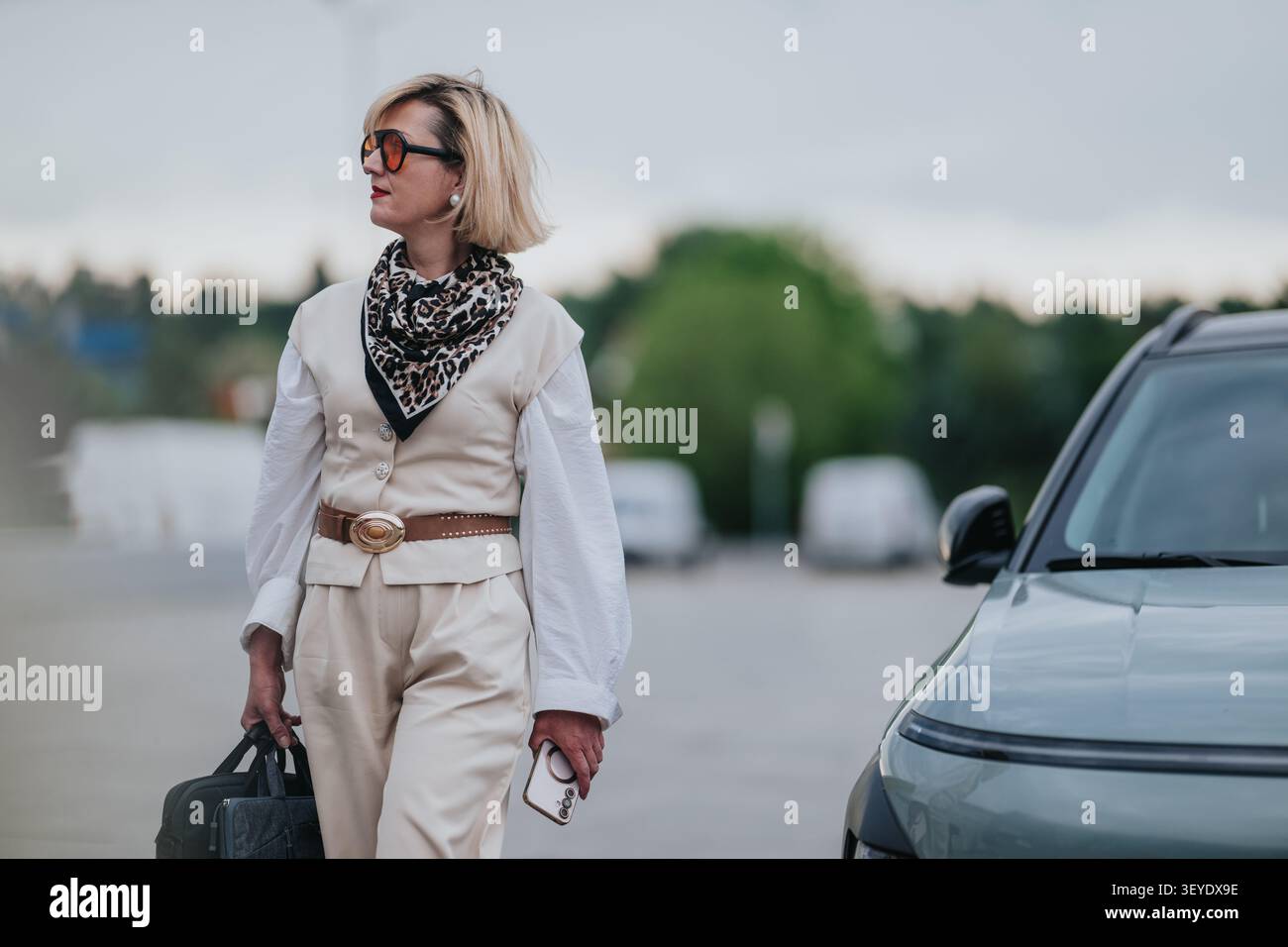 Donna d'affari che arriva in auto con bagagli e telefono, lavoro a distanza e stile di vita da viaggio Foto Stock