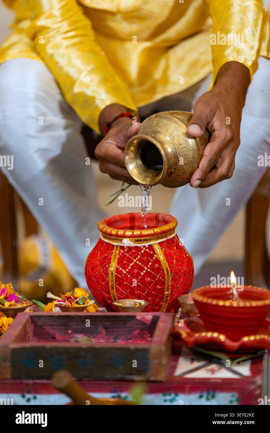 Rituale indù con acqua che versa in un vaso decorato durante una cerimonia Foto Stock