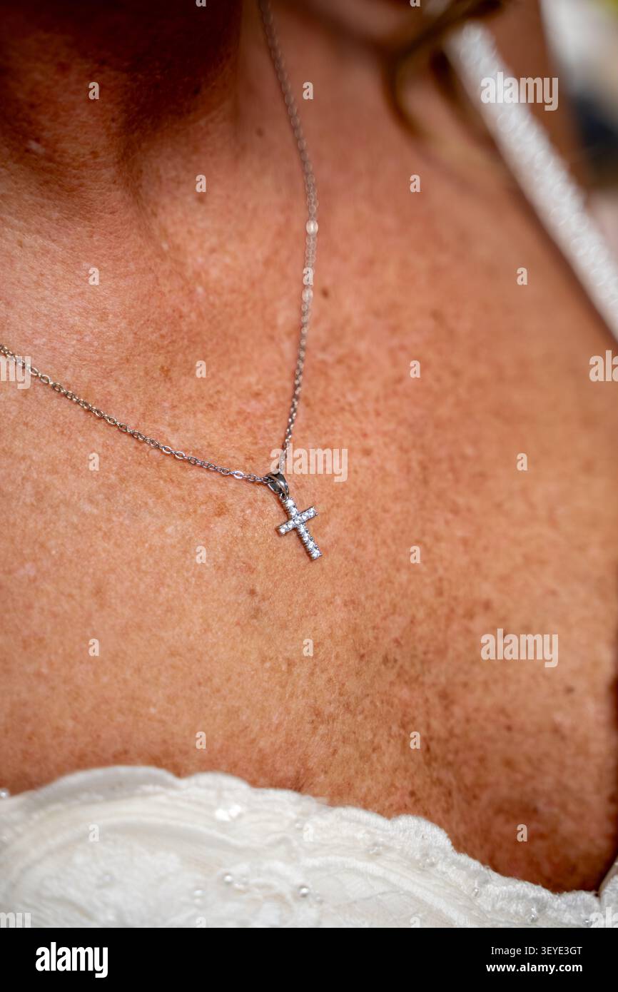 Primo piano della sposa che indossa una collana con pendente a croce in argento. Foto Stock