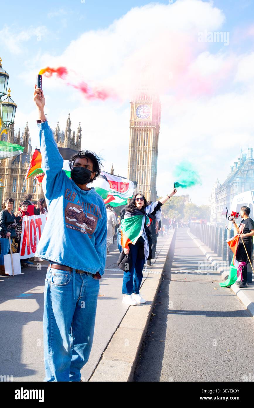 I manifestanti tengono razzi luminosi sul Ponte di Westminster per commemorare lo sciopero delle donne islandesi del 1975 durante una manifestazione pro-Palestina, ottobre 2024 Foto Stock