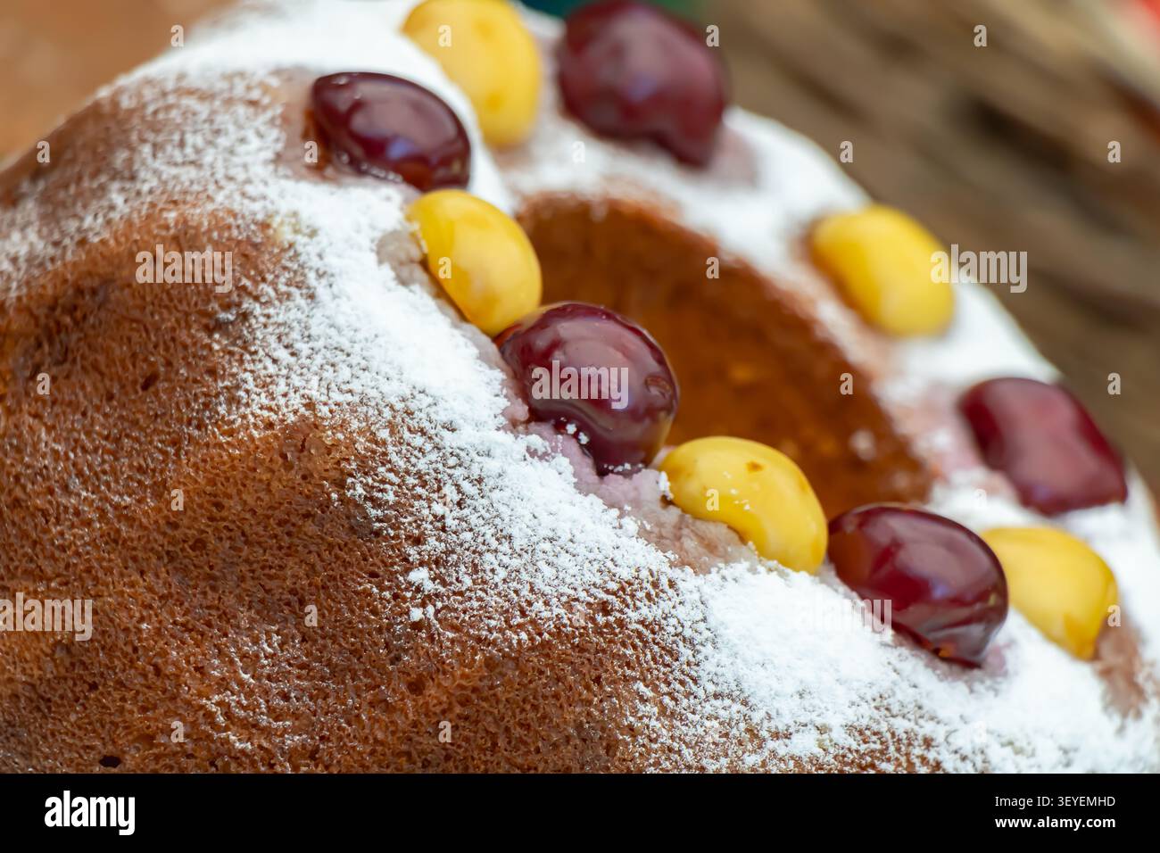 Primo piano della tradizionale torta fatta in casa spolverata con zucchero a velo e decorata con ciliegie dolci gialle fresche e scure in un cibo artigianale locale Foto Stock
