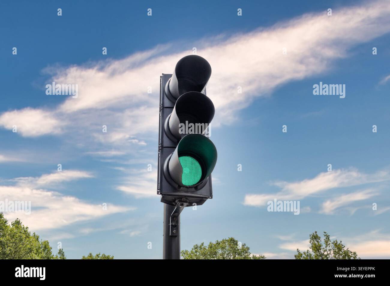 Semaforo verde che splende contro un cielo blu con nuvole Foto Stock