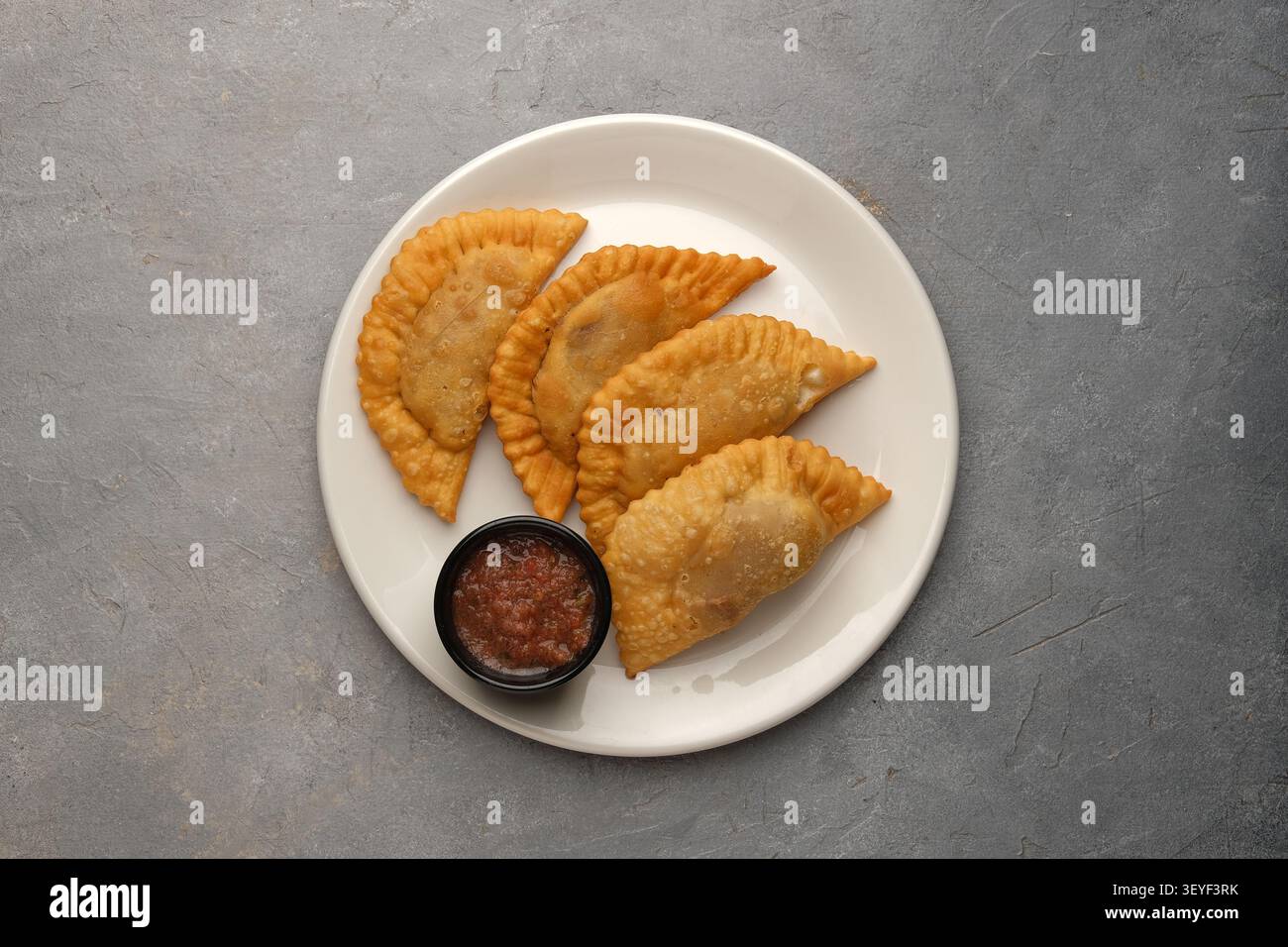Piatto bianco di paillettes fritte dorate con salsa rossa su sfondo grigio Foto Stock