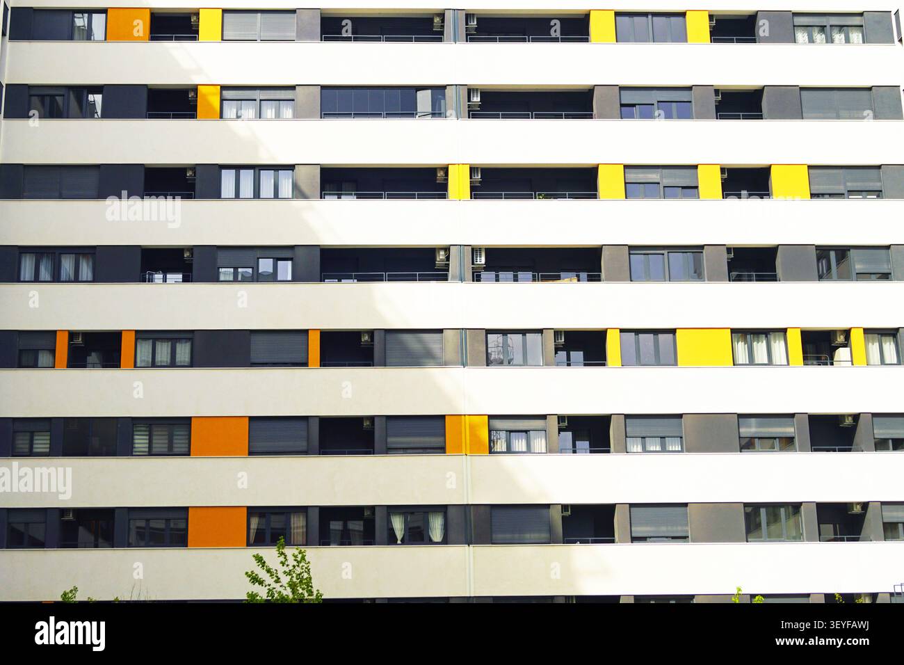 Facciata di appartamento con fasce di balconi ripetitive e pannelli di accento contrastanti. Progettazione architettonica modulare e organizzazione spaziale ripetitiva. Foto Stock