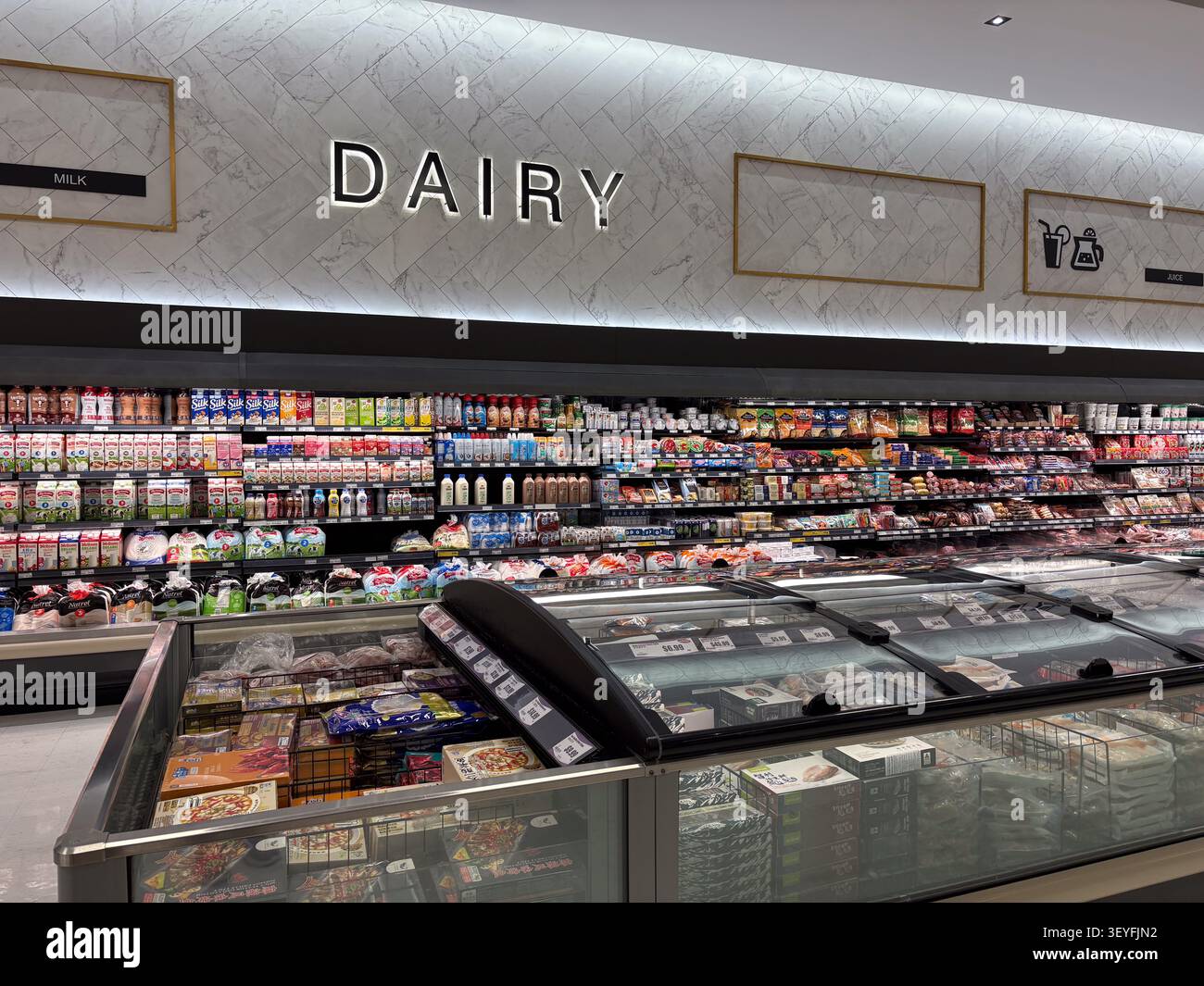 Scaffali refrigerati e contenitori per congelatori che espongono prodotti lattiero-caseari e alimenti in un corridoio di supermercato. Foto Stock