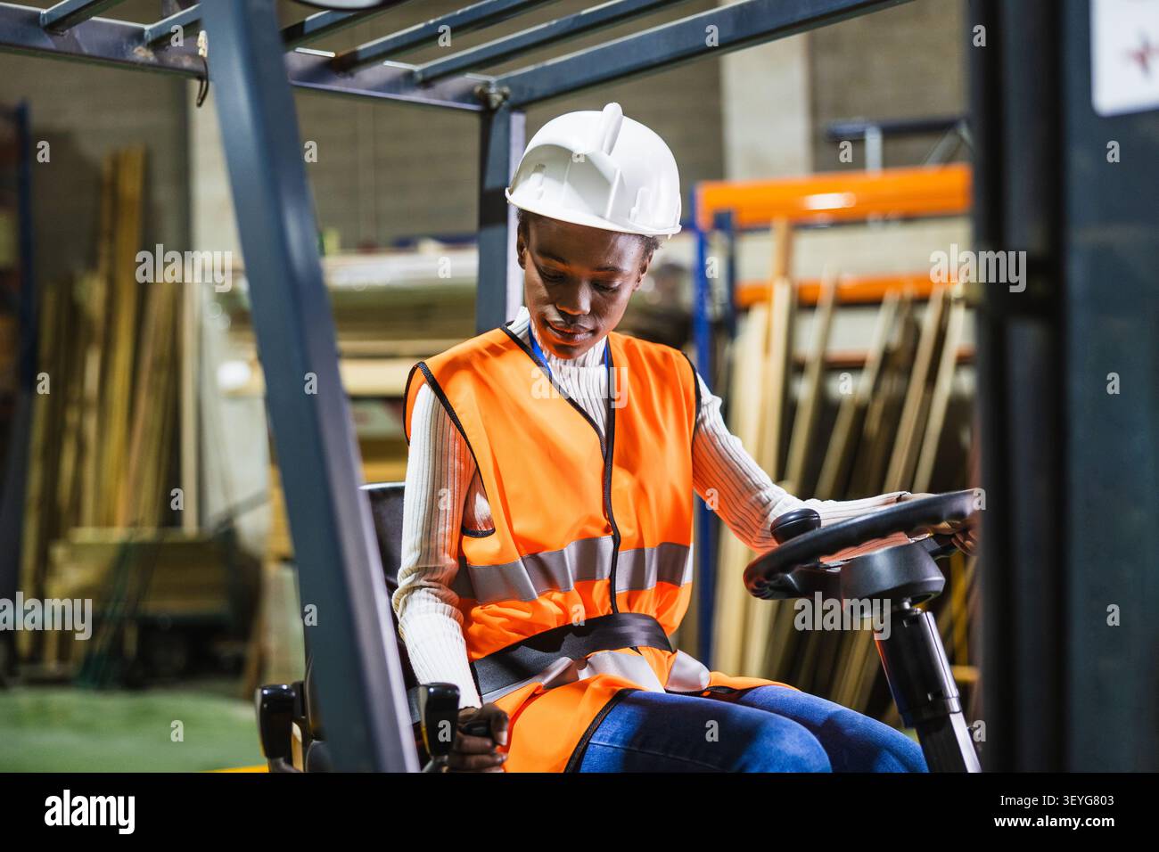 Lavoratrice che lavora su carrelli elevatori in un magazzino di stabulazione Foto Stock