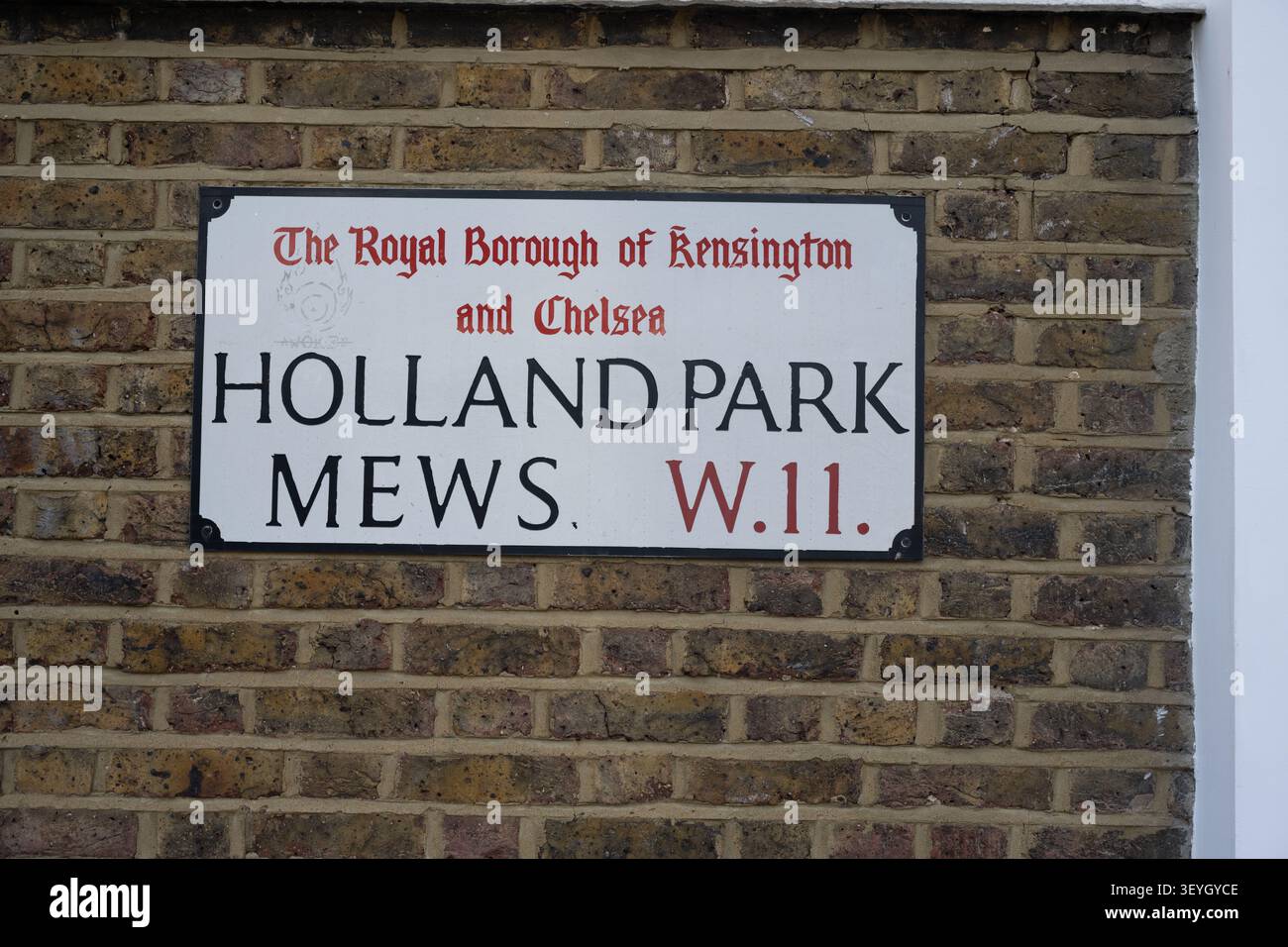 Un chiaro cartello stradale per 'HOLLAND PARK MEWS W.11' montato su una parete in mattoni testurizzati nel Royal Borough di Kensington e Chelsea, Londra, Regno Unito. Foto Stock