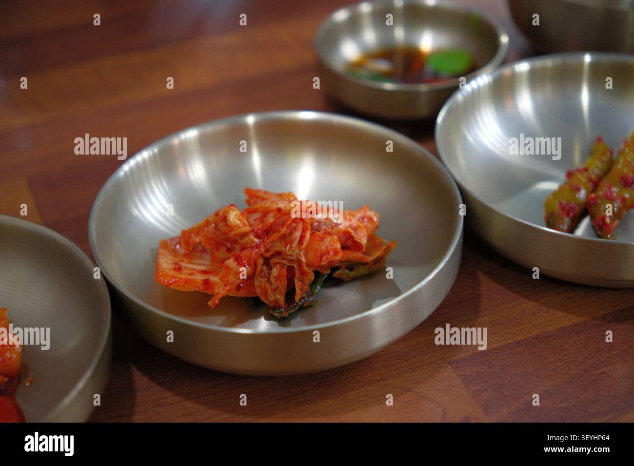 Kimchi e contorni coreani (banchan) serviti in ciotole di acciaio inossidabile Foto Stock