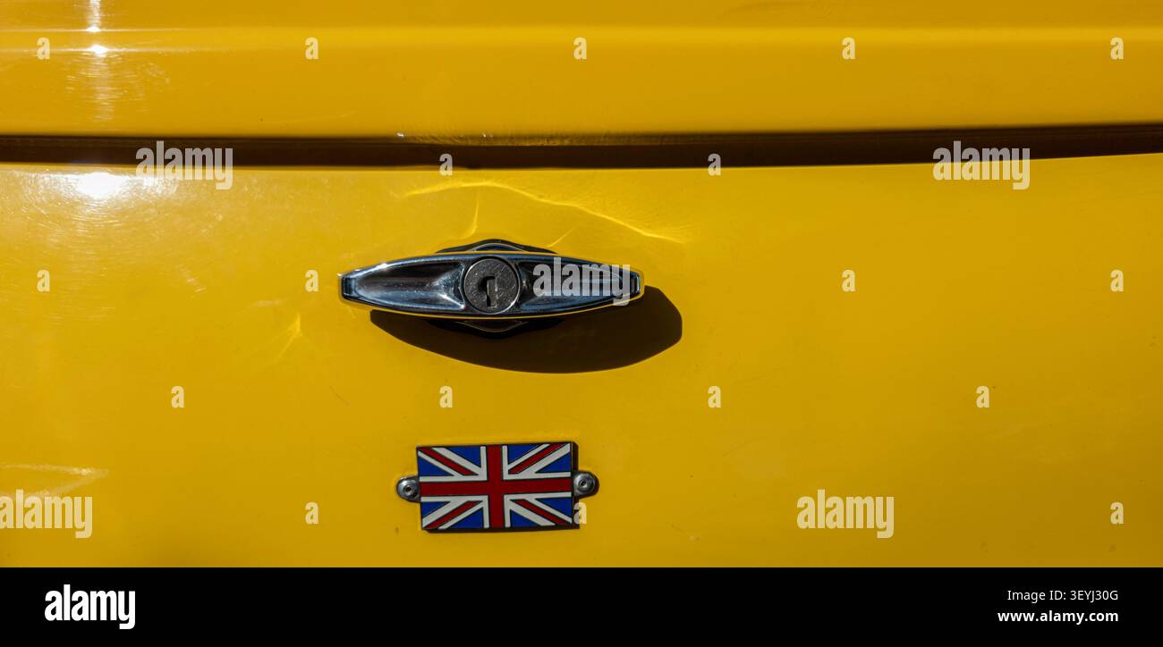 TAVERNES BLANQUES, SPAGNA - 14 GIUGNO 2026. Il manico del bagagliaio di una Mini Cooper gialla mostra dettagli cromati e il logo British Union Jack. Questo primo piano Foto Stock