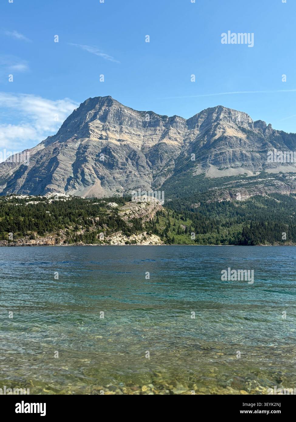Le aspre cime delle Montagne Rocciose canadesi si innalzano sopra le acque cristalline del lago Waterton, del Waterton Lakes National Park, Alberta, Canada. - Immagine stock catturata con smartphone
