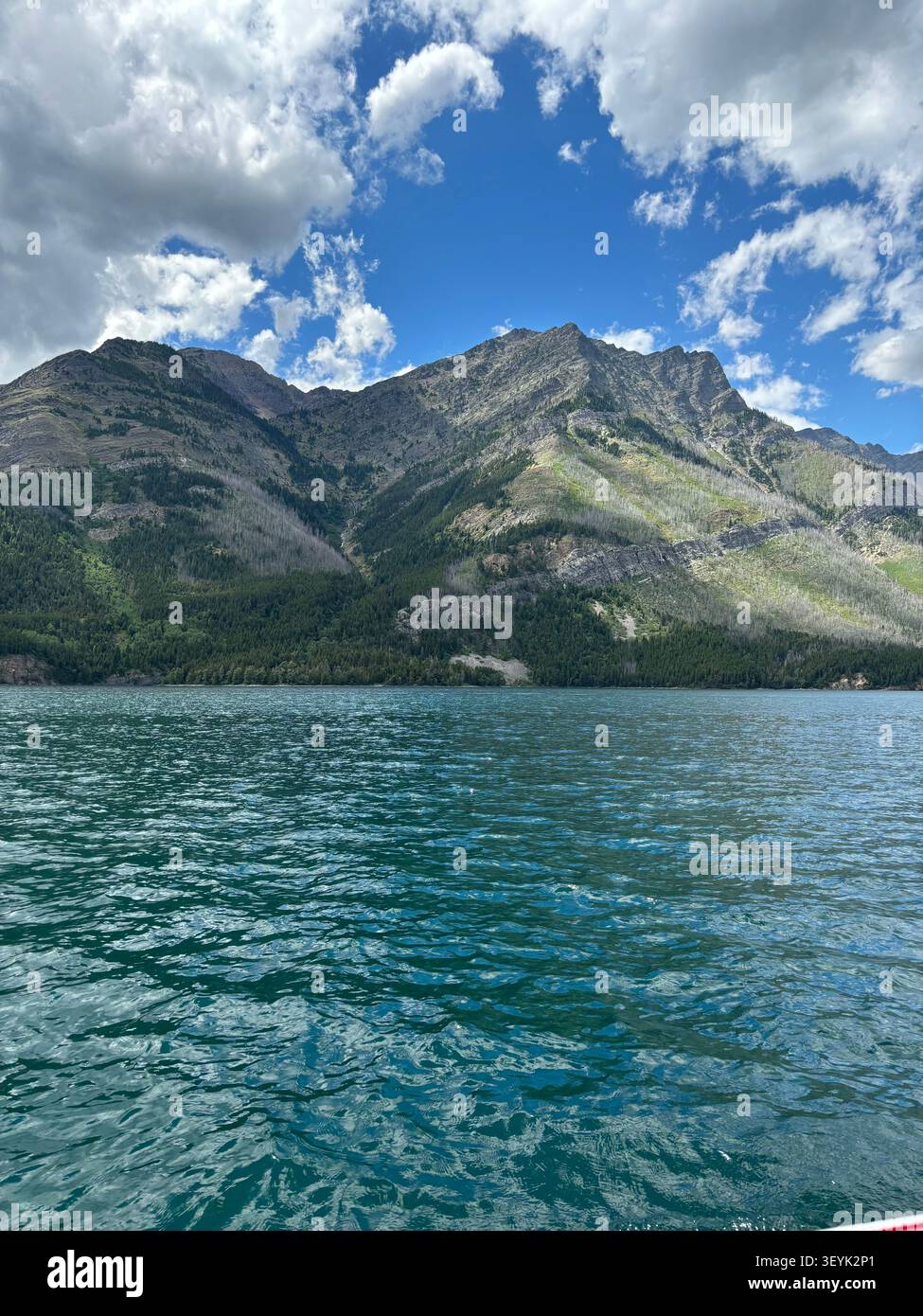 Le aspre cime delle Montagne Rocciose canadesi si innalzano sopra le acque cristalline del lago Waterton, del Waterton Lakes National Park, Alberta, Canada. - Immagine stock catturata con smartphone