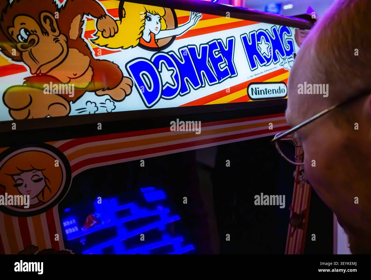 Visitatore che gioca al classico gioco arcade per Nintendo Donkey Kong su una macchina arcade originale durante un evento di gioco rétro. Foto Stock